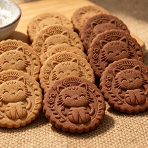 A batch of beautifully embossed cookies in light and dark brown, featuring a detailed 3D smiling cat design made with a handcrafted 4x4 inch wooden cookie mold
