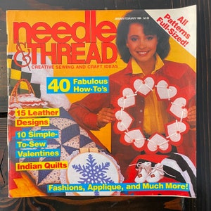 May include: A magazine cover for Needle & Thread, a creative sewing and craft ideas magazine. The cover features a woman wearing a red shirt holding a wreath of red and white hearts. The cover text includes "40 Fabulous How-To's", "15 Leather Designs", "10 Simple-To-Sew Valentines", "Indian Quilts", "Fashions, Applique, and Much More!" and "All Patterns Full-Sized!"