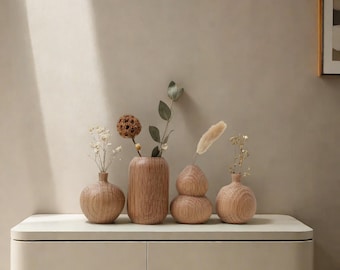 May include: Four wooden vases of different shapes and sizes, arranged on a light beige surface. The vases are all made of natural wood and have a rustic, handcrafted look. The vases are filled with dried flowers and greenery.