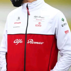 Puede incluir: Chaqueta de carreras Alfa Romeo Racing blanca y roja con cremallera negra. La chaqueta presenta varios logotipos, incluyendo "Alfa Romeo", "Carrera" y "Orlen". Las mangas son blancas y la parte inferior de la chaqueta es roja.