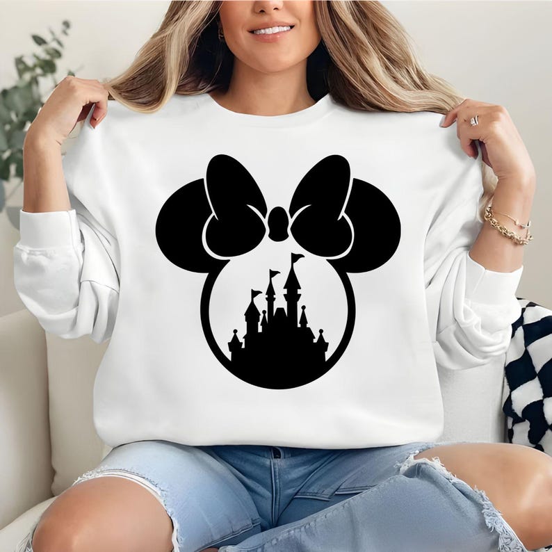Puede incluir: Sudadera blanca con un dise&ntilde;o negro de Minnie Mouse, que incluye un lazo y una silueta de castillo. El gr&aacute;fico est&aacute; centrado en la parte delantera de la parte superior de manga larga. La sudadera es de material suave.
