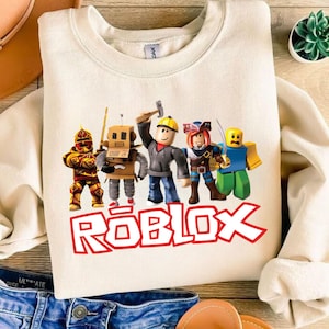 Peut inclure: Sweat-shirt cr&egrave;me avec un graphisme color&eacute; de personnages Roblox. Le mot "ROBLOX" est imprim&eacute; en lettres rouges en dessous des personnages. Le sweat-shirt est fait d'une mati&egrave;re douce.