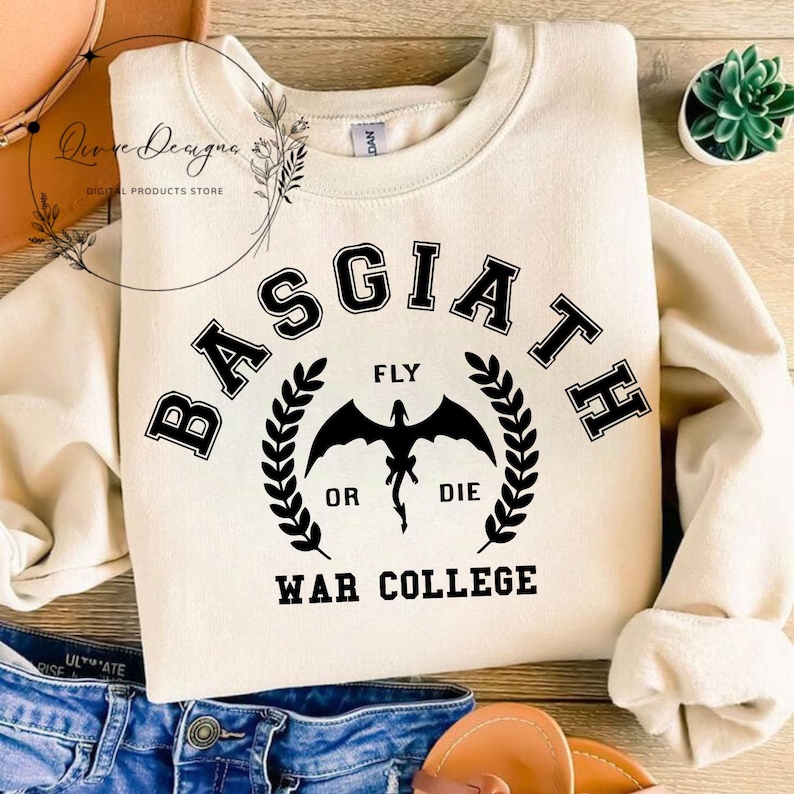 May include: A cream-colored sweatshirt with a black graphic design. The graphic features a dragon with the text "Basgiath", "Fly or Die", and "War College".