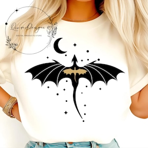 May include: A white t-shirt with a black silhouette of a dragon with gold accents flying against a background of a crescent moon and stars.