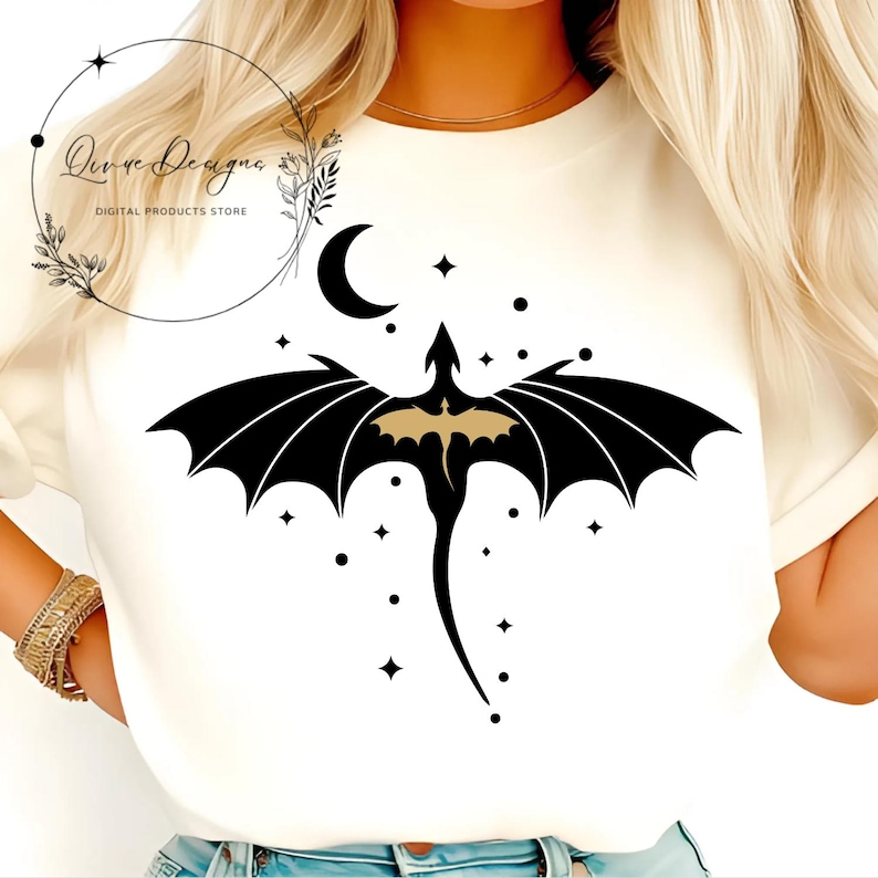 May include: A white t-shirt with a black silhouette of a dragon with gold accents flying against a background of a crescent moon and stars.