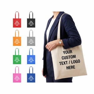 May include: A beige canvas tote bag with the black text YOUR CUSTOM TEXT / LOGO HERE printed on the front. Eight smaller tote bags in red, black, orange, gray, green, blue, pink, and dark blue are displayed in a grid, each with custom text.
