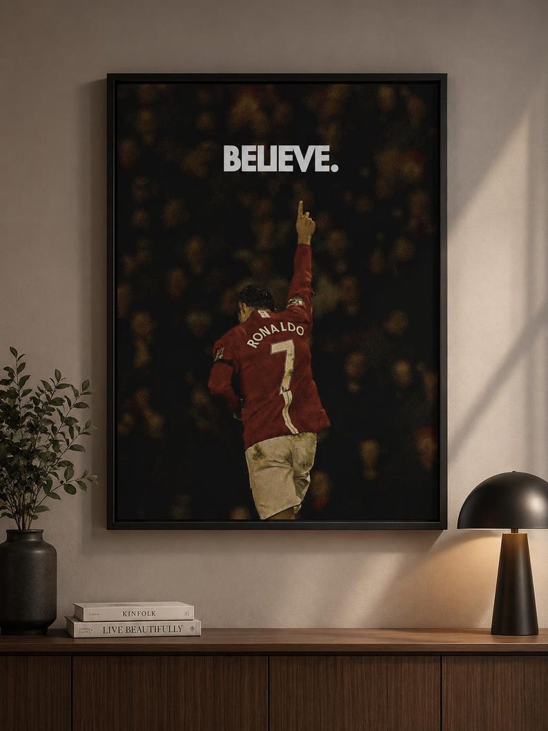 May include: A framed wall art print featuring a soccer player from behind, wearing a red jersey with the name RONALDO and the number 7 on the back. The player has one arm raised, and the word BELIEVE is printed in white above the figure.