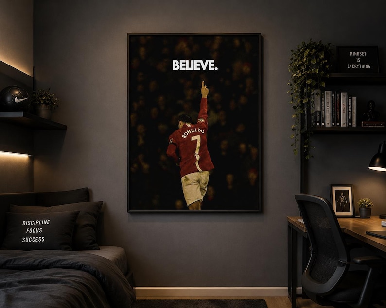 May include: A framed rectangular wall art print featuring a soccer player wearing a red jersey with the name RONALDO and the number 7 on the back, pointing a finger upward. The word BELIEVE. is printed in white capital letters above the player.