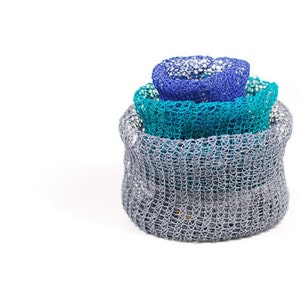 May include: Three crocheted bowls, stacked on top of each other. The top bowl is blue, the middle bowl is teal, and the bottom bowl is gray.