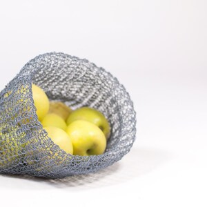 May include: A gray mesh bag filled with yellow apples. The bag is made of a soft, flexible material and is perfect for carrying fruit or vegetables.