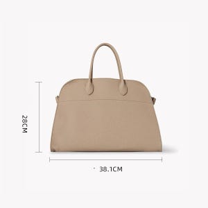 Puede incluir: Bolso de mano beige con dos asas y una parte superior curvada. El bolso mide 28 cm de alto y 38,1 cm de ancho. El bolso tiene un dise&ntilde;o sencillo y elegante.