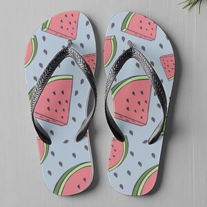 May include: A pair of flip-flops featuring a watermelon design on a light blue background. The watermelon slices are pink with green outlines and black seeds. The straps are black and silver.