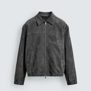 May include: A charcoal-colored suede jacket with a collared neckline and a full-length zipper. The jacket features a classic design with a slightly distressed appearance, elastic cuffs, and a hem. The jacket has two front pockets.