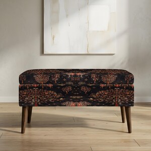 May include: A rectangular ottoman with a dark background and a repeating pattern of trees in shades of orange and brown. The ottoman has four wooden legs and is placed in a room with a neutral color palette.