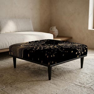 Puede incluir: Un otomán negro con un diseño floral dorado. El otomán rectangular tiene cuatro patas negras y un marco negro. La parte superior presenta un patrón repetido de líneas y puntos dorados, creando un aspecto elegante y moderno.