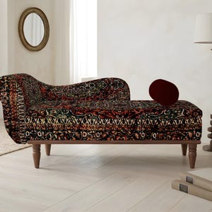 May include: A chaise longue with a patterned fabric in shades of red, black, and green. The wooden frame has four legs. A burgundy cushion rests on the chaise. The room also features a floor lamp, a mirror, and a vase.