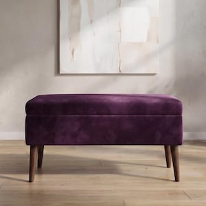 May include: A rectangular storage bench upholstered in deep purple velvet fabric. The bench features a smooth, flat top and a solid base supported by four tapered wooden legs in a medium brown finish, providing a stable and elevated structure.