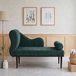 May include: A teal green chaise lounge with a curved back and armrest. The lounge has a corduroy texture and sits on black legs. Two framed botanical prints hang on the wall behind the lounge.