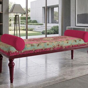 May include: A maroon bench with a patterned cushion in shades of pink, green, and gold. It has two cylindrical backrests and four maroon, turned legs. The bench is approximately 60 inches long.