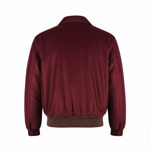 May include: A burgundy corduroy jacket with a brown ribbed hem and cuffs. The jacket has a collared neckline and buttoned cuffs. The back view of the jacket is shown against a white background.
