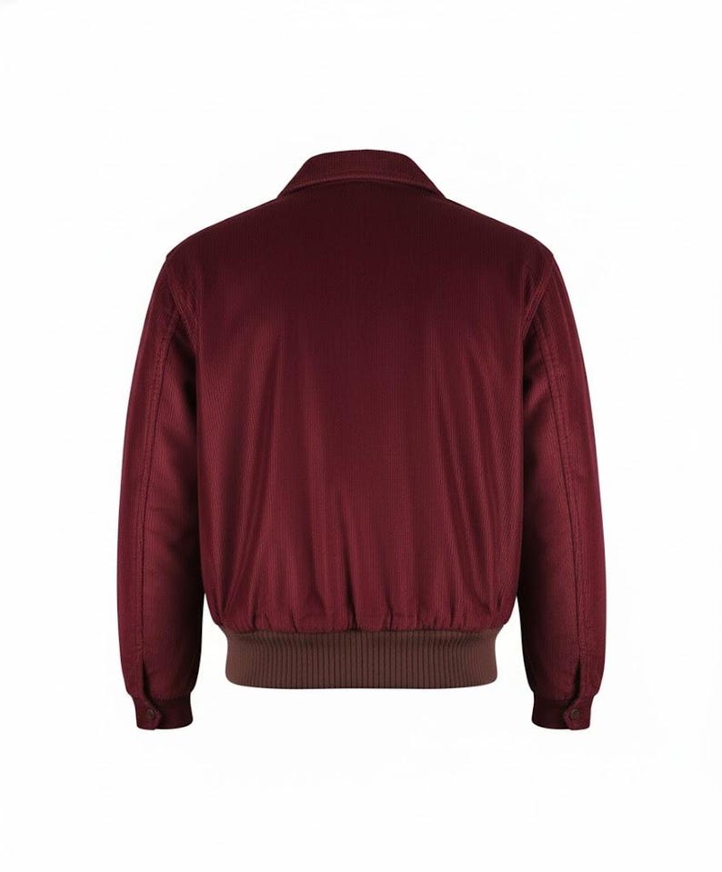May include: A burgundy corduroy jacket with a brown ribbed hem and cuffs. The jacket has a collared neckline and buttoned cuffs. The back view of the jacket is shown against a white background.