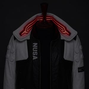 May include: A black and white jacket featuring the text NUSA printed vertically on the chest. The garment includes a high collar with glowing red linear accents, three circular buttons on each sleeve, and a dark central panel with a zipper.
