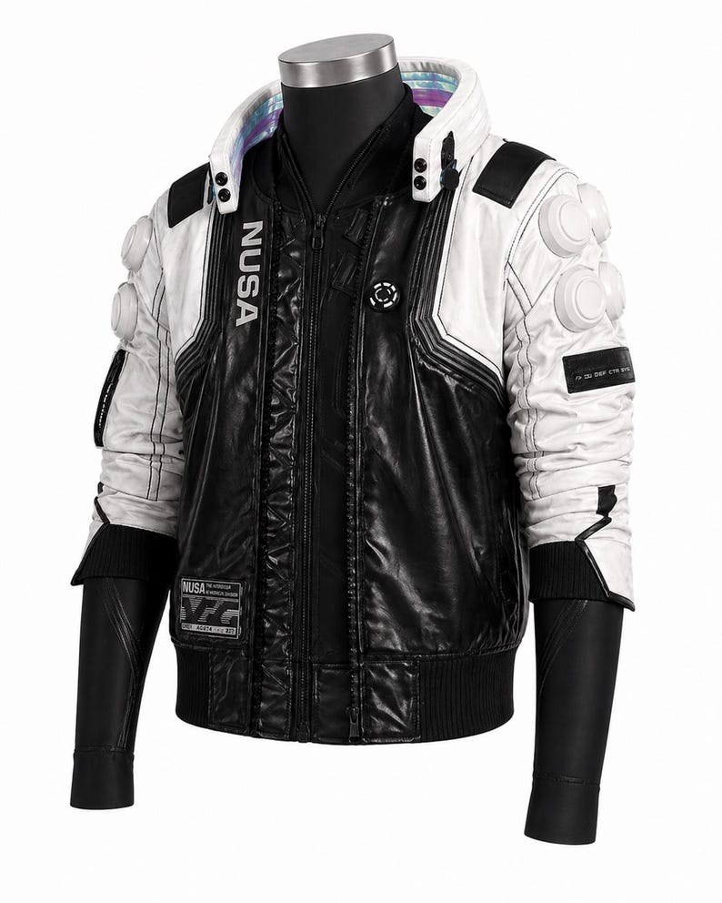 May include: A black and white jacket featuring a high collar with iridescent trim, white shoulder pads with circular accents, and the text NUSA printed vertically on the chest. The garment includes a front zipper, black sleeves, and rectangular patches.