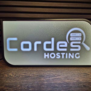 May include: A rectangular sign with the text "Cordes HOSTING" in white and light blue. The sign has a black border and a graphic of a magnifying glass over server racks. The background is a gradient of white and light green.