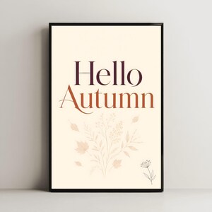Peut inclure: Une affiche murale rectangulaire dans un cadre noir avec le texte Hello Autumn en police serif violet foncé et orange brûlé. Sous le texte se trouve une illustration beige clair de diverses feuilles, tiges et une petite fleur.
