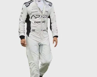 May include: A white and black racing jumpsuit featuring the text APXGP, Shark Ninja, IWC, and Expensify, with OMP branding on the chest and shoulders. The suit includes a white mock neck collar, black side panels, and a small American flag patch.