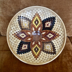 May include: A wooden bowl with a geometric pattern in shades of brown, black, and yellow. The bowl is made of wood and has a smooth, polished finish.
