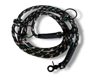 May include: A black and green rope dog leash with two metal clips. The leash is made of a thick, durable rope and has a camouflage pattern.