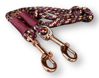 May include: A maroon, gray, and gold rope dog leash with two rose gold swivel clips.