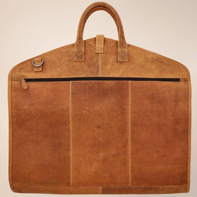 Foldable handmade leather suit carrier designed for easy travel – rustic garment bag for men’s business or wedding trips.