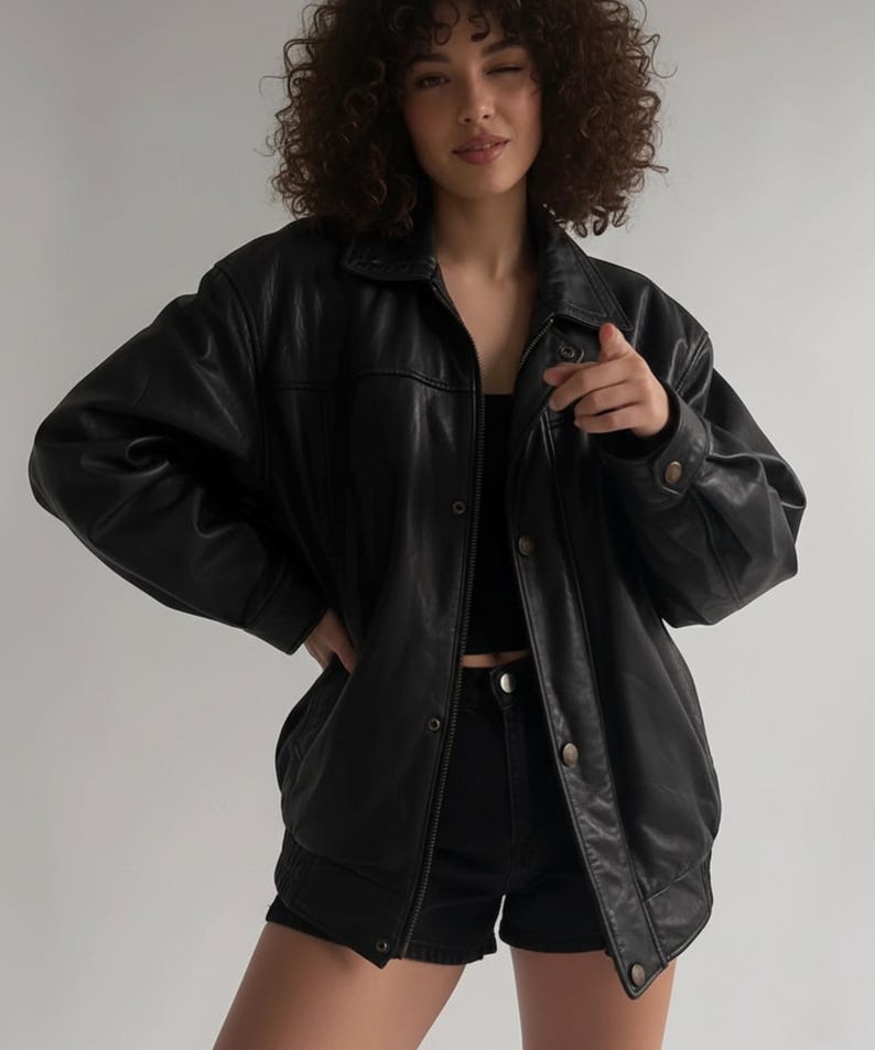 Black oversized women’s leather bomber jacket shown on a model, featuring sheepskin construction, quilted interior, and a vintage-inspired winter coat design. Styled for 90s fashion lovers and those seeking warm, durable fall and winter outerwear. Ideal gift for her, offering comfort, style, and a relaxed streetwear fit.