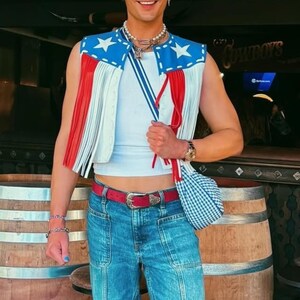 Unisex American Flag leather fringe vest, handmade patriotic festival jacket, genuine leather cowboy vest, custom Western wear for men and women, rustic vintage leather vest for country concerts and events.