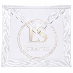 May include: A white square apron featuring a triangular flap at the top and a satin-like border. Centered on the fabric is a circular logo in a light gold tone containing the letters LS and the word CRAFTS positioned below a horizontal line.