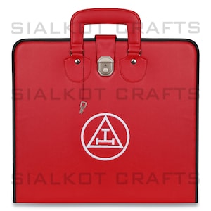 May include: Red leather carrying case with a black trim and a silver lock and key. The case has a white embroidered symbol of a triangle with a cross inside, surrounded by a circle.