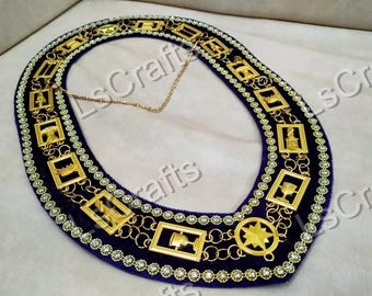 May include: A dark blue collar with gold-colored rectangular and circular embellishments. The collar is lined with small, clear rhinestones and connected by a gold chain. The rectangular embellishments feature various symbols.