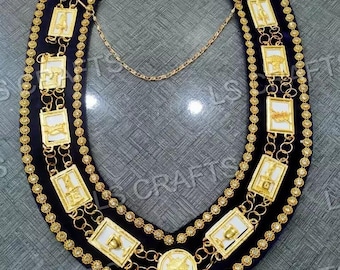 May include: A gold and white collar chain with a blue velvet backing. The chain features multiple rectangular medallions with intricate designs.