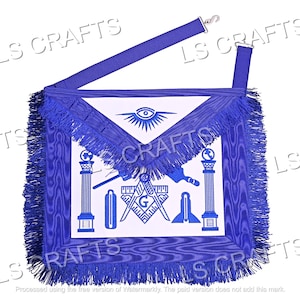 Puede incluir: Un delantal masónico azul con flecos blancos y símbolos bordados, incluyendo un compás, una escuadra y un ojo que todo lo ve. El delantal tiene una correa azul con una hebilla plateada.