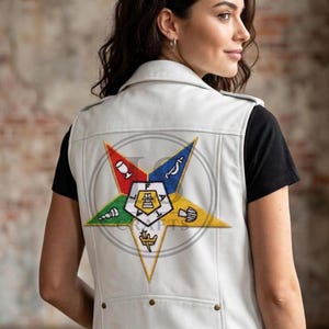 May include: A white leather vest featuring a large, colourful embroidered emblem on the back. The emblem is a five-pointed star with various symbols and a central design. The vest has a classic design with a collar and snap closures.