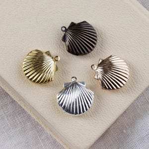 May include: Four different coloured metal seashell charms. The charms are in gold, silver, rose gold and bronze.