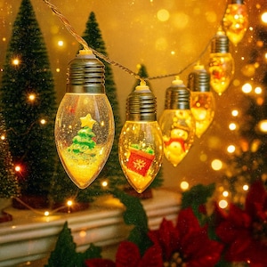 以下が含まれることがあります： クリスマスの装飾的なストリングライト。各クリア電球には、クリスマスツリー、ギフト、雪だるまなど、ミニチュアのクリスマスのシーンが含まれています。ライトは茶色のワイヤーに繋がれており、暖かく金色の背景があります。