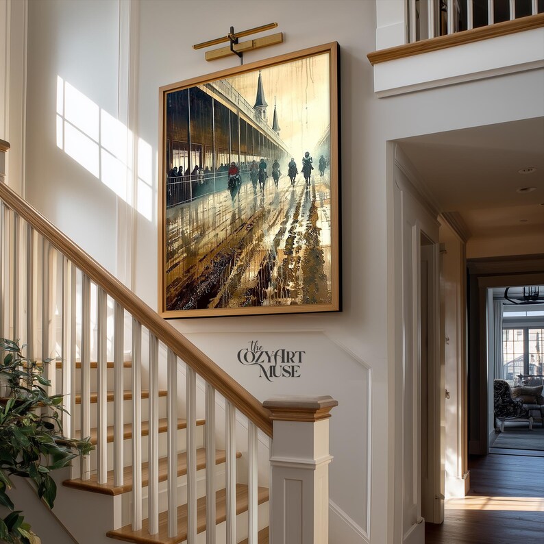 May include: A framed art print depicting a horse race in a rainy setting. The artwork features a long, covered structure with people, and several horses with riders racing on a wet track. The print is in a wooden frame and hangs on a white wall.