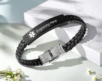 May include: Black braided leather bracelet with a stainless steel clasp. The bracelet has a black metal plate with the text "Engraving Here" and a medical symbol.