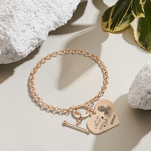 May include: Rose gold bracelet with a heart-shaped charm. The charm features a photo and the inscription "I Am Always With You" and the name "William". The bracelet has a toggle clasp.