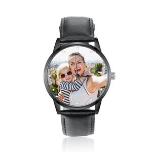Puede incluir: Reloj de pulsera negro con esfera redonda que muestra una fotograf&iacute;a en color de una mujer y un ni&ntilde;o. El reloj tiene un bisel negro, una correa de cuero negro y una corona plateada. La esfera tiene peque&ntilde;os marcadores de hora de puntos blancos.