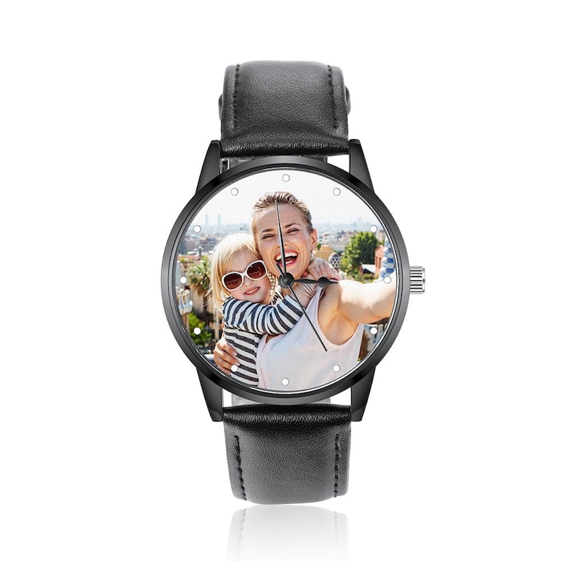 Puede incluir: Reloj de pulsera negro con esfera redonda que muestra una fotograf&iacute;a en color de una mujer y un ni&ntilde;o. El reloj tiene un bisel negro, una correa de cuero negro y una corona plateada. La esfera tiene peque&ntilde;os marcadores de hora de puntos blancos.
