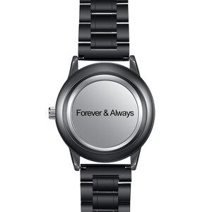 Op de afbeelding: Een zwart polshorloge met een zilveren wijzerplaat. De wijzerplaat toont de woorden "Forever & Always" in een eenvoudig lettertype. Het horloge heeft een zwarte metalen band.